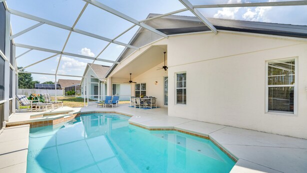 A covered swimming pool with a glass ceiling, adjacent lounge chairs, and a patio area with a table and chairs. - 10 Mi to Disney: Home w/ Spa & Heated Pool! (Davenport)