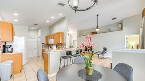 A modern kitchen with wooden cabinets, a central island, and a dining area with a round table and chairs. - 10 Mi to Disney: Home w/ Spa & Heated Pool! (Davenport)