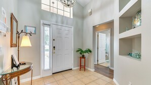 A hallway with a white door, a glass table, a lamp, and a potted plant. - 10 Mi to Disney: Home w/ Spa & Heated Pool! (Davenport)