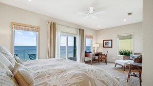 Ein Schlafzimmer mit Bett, Schreibtisch, Stuhl und Blick auf den Ozean.