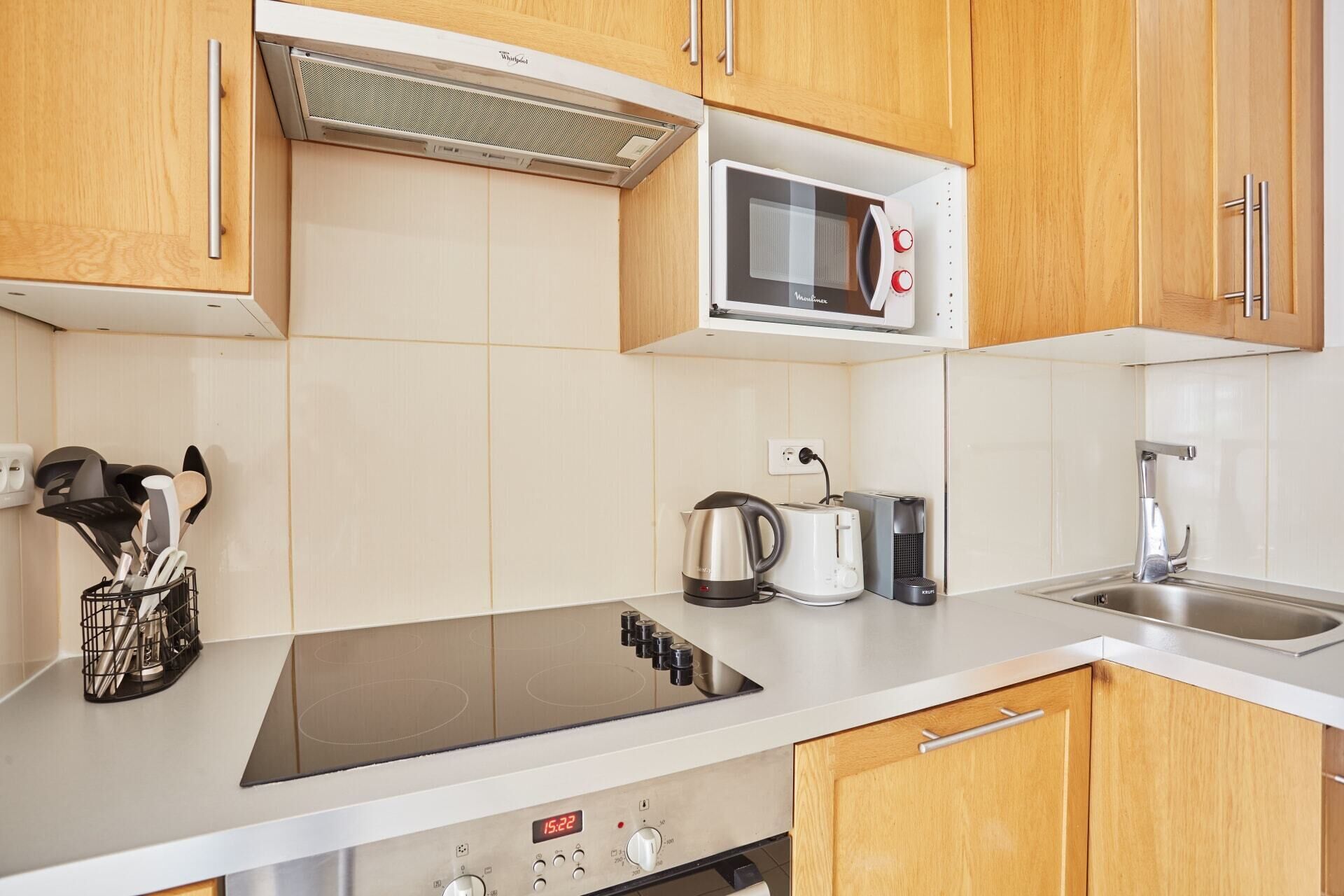 Eine moderne Küche mit Holzausstattung, einer integrierten Mikrowelle, einem Wasserkocher, einem Toaster und einem Geschirrspüler.
