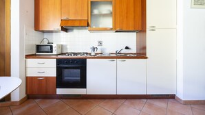 A compact kitchen with wooden cabinets, a microwave, an oven, and a refrigerator. - Faenza 91 Apartament (Firenze)