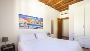 A bedroom with a bed, a nightstand, a lamp, a painting, and a wardrobe. - Faenza 91 Apartament (Firenze)