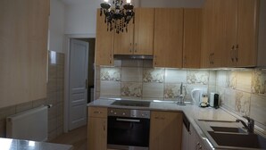 Eine Küche mit Holzausstattung, einem Edelstahlbackofen, einer Spüle und einer Kristallleuchtre.
