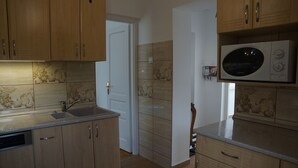 Eine Küche mit Holzschränken, einer Edelstahl-Spüle und einer Mikrowelle.