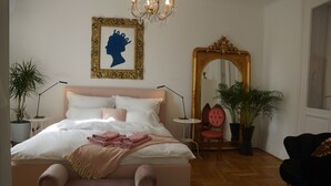 Ein Schlafzimmer mit einem großen Bett, einem Spiegel und zwei Blumentöpfen.