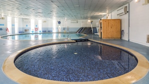 A large indoor swimming pool with a tiled floor and a wooden door on the right. - 42 Valley Lodge (Gunnislake)