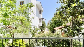 Un balcon avec deux fauteuils en osier et une petite table ronde.