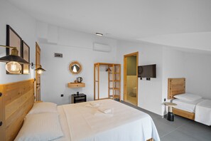 A modern bedroom with a wooden headboard, a large bed, a smaller bed, a bedside table, a mirror, and a television. - Egeden Hotel (Datça)