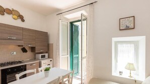 A compact kitchen with a dining area, a washing machine, and a window with a lamp.