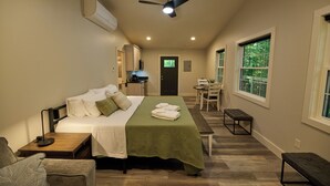 Ein Hotelzimmer mit Bett, Schreibtisch, Stuhl, Bank, Deckenventilator und Fenster.