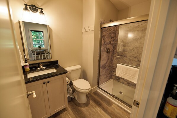 A bathroom with a toilet, sink, and a glass-enclosed shower area.