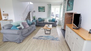 A modern living room with two grey sofas, a wooden coffee table, and a TV on a wooden cabinet. - Turning Tide (Chathill)