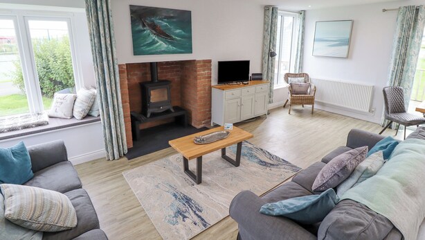 A modern living room with a fireplace, comfortable seating, and artwork on the walls. - Turning Tide (Chathill)