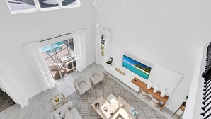 Un amplio salón con un televisor grande, asientos cómodos y vistas al exterior.