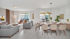 Uma sala de estar moderna com um sofá cinza, uma mesa de centro e uma área de jantar com uma mesa e cadeiras de madeira.
