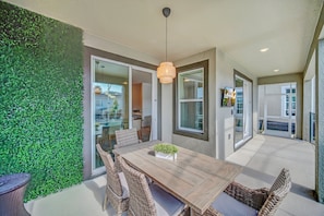 Enjoy dining al fresco in this serene outdoor space with a wooden table and wicker chairs.