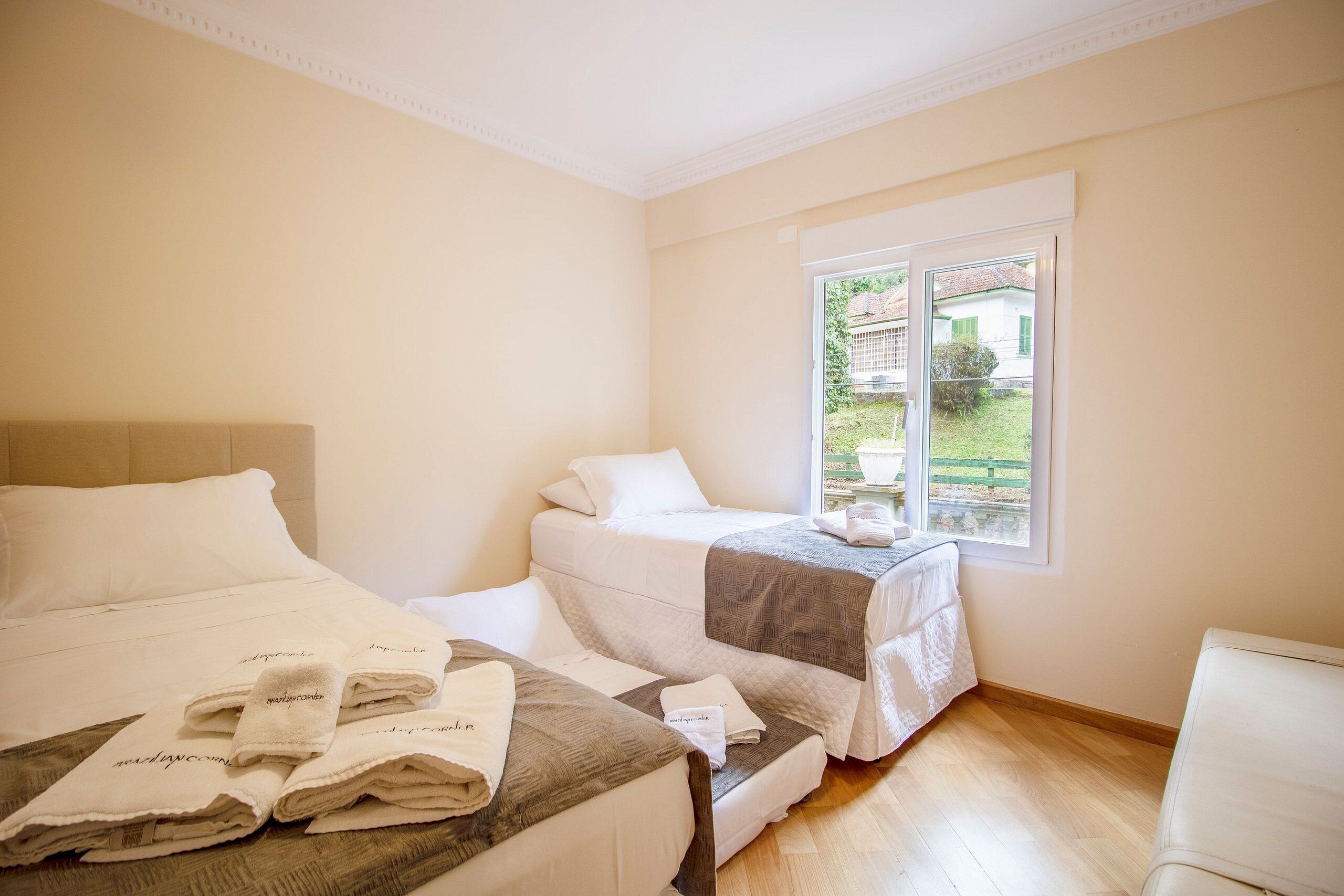 A hotel room with two beds, a large window, and a view of the outside.