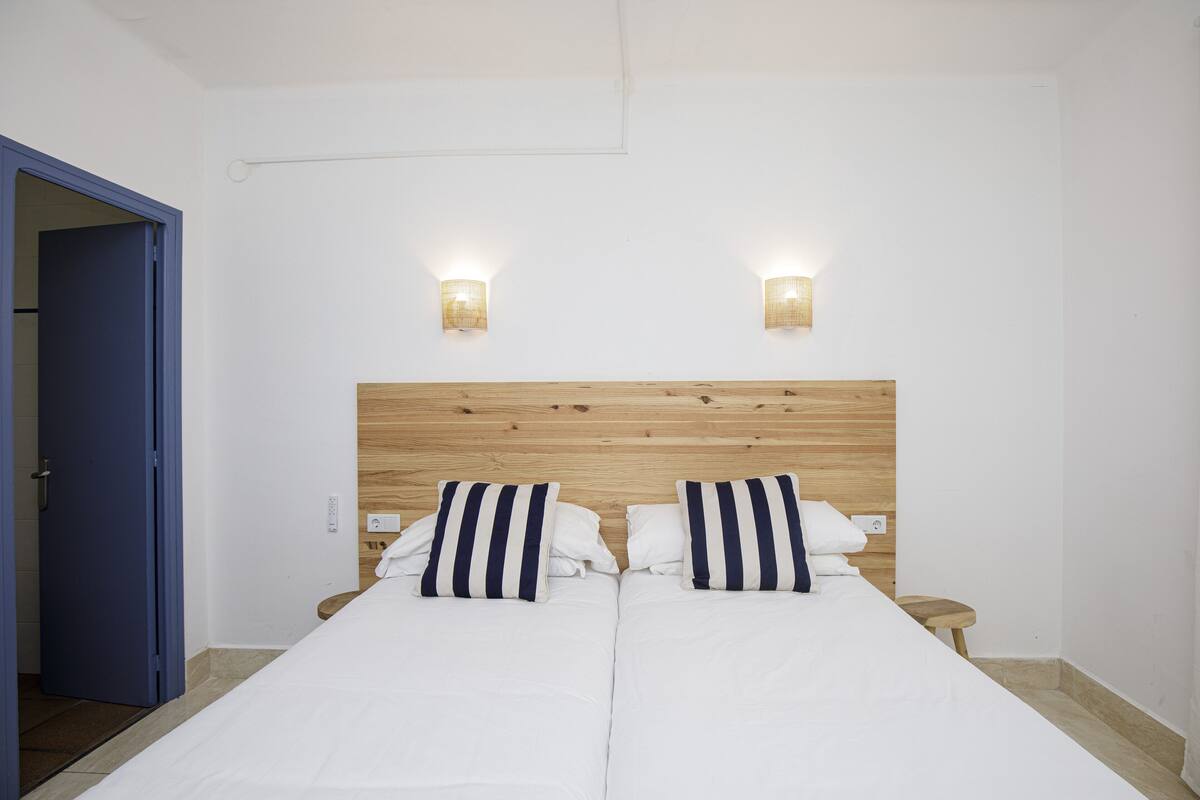 Ein Doppelbett mit zwei Kissen, einem Holzkopfstück und zwei Wandleuchten.