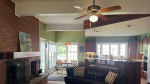 A living room with a fireplace, a sofa, and a dining area with a table and chairs. - 1878 Victorian Charmer (Endicott)
