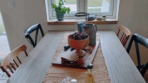 A dining table with a placemat, a bowl of fruit, a pitcher, and a bottle of water. - Small house in cozy village near the sea (Ystad)