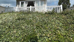 A mobile home with a white exterior, a porch, and a white fence. - Poppy, dog-friendly caravan with panoramic sea views on Rockley Park Poole wi-fi (Poole)