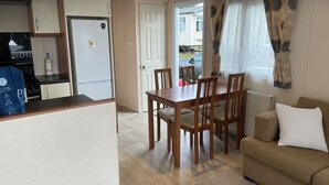 A compact living space with a kitchenette, dining area, and seating area. - Poppy, dog-friendly caravan with panoramic sea views on Rockley Park Poole wi-fi (Poole)