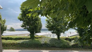 A residential area with neatly trimmed hedges, a paved road, and houses with sloped roofs. - Poppy, dog-friendly caravan with panoramic sea views on Rockley Park Poole wi-fi (Poole)