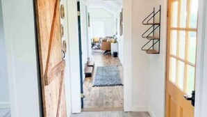 Un pasillo con puerta de madera, alfombra y lámpara en el techo.
