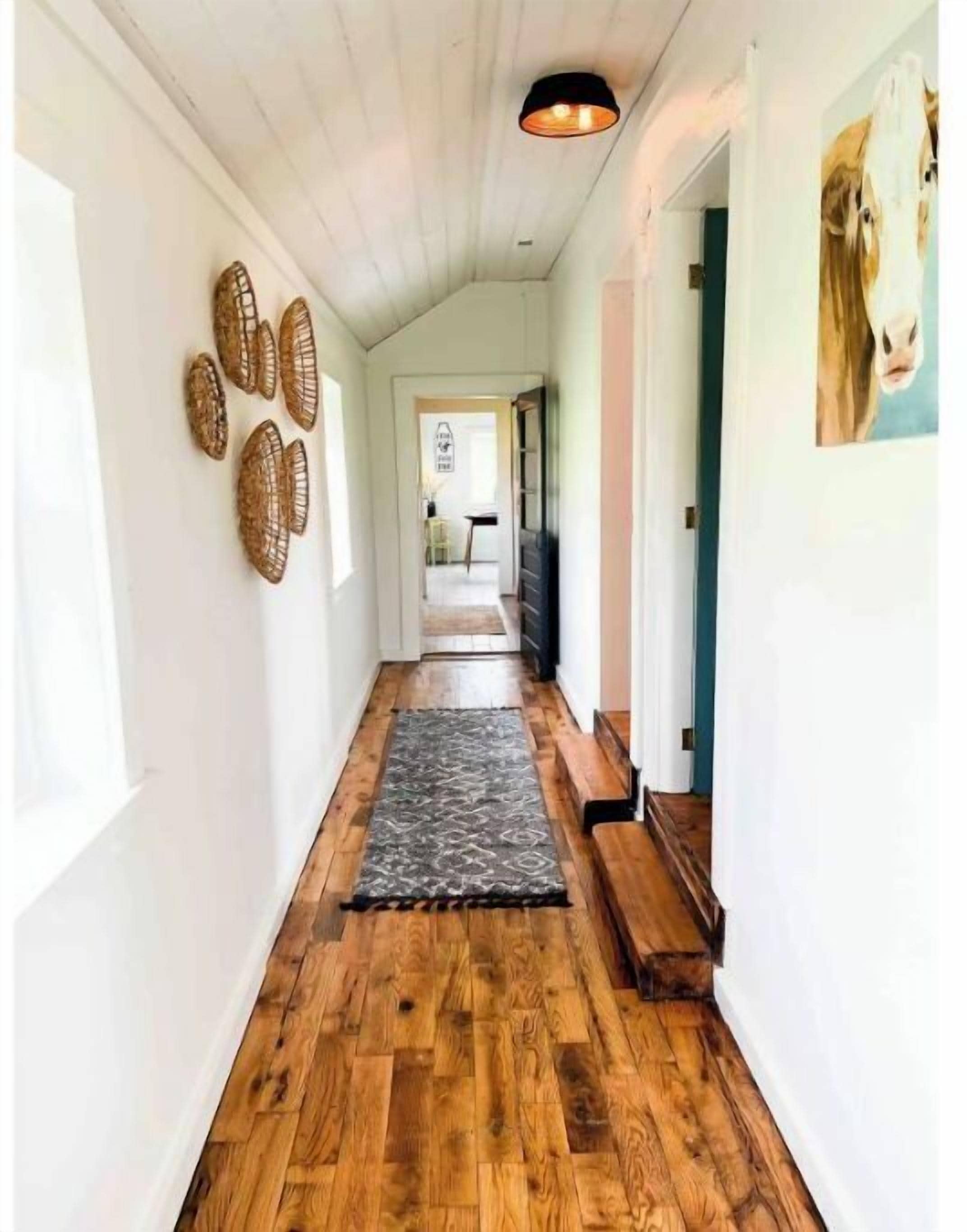 Ein Flur mit Holzboden, einem gemusterten Teppich und an der Wand befestigten Dekorationselementen.