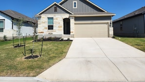 A modern two-story house with a stone facade, a garage, and a well-maintained lawn. - Country Cozy! Well stocked, immaculate home. Great short or extended stays!   
 (Jarrell)