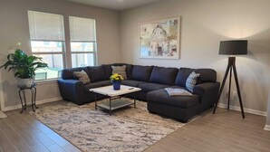 A living room with a sectional sofa, a coffee table, a floor lamp, and a painting on the wall. - Country Cozy! Well stocked, immaculate home. Great short or extended stays!   
 (Jarrell)