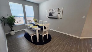 A dining area with a white table and chairs, a potted plant, and a wall-mounted artwork. - Country Cozy! Well stocked, immaculate home. Great short or extended stays!   
 (Jarrell)