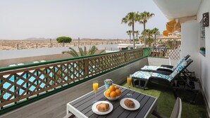 Ein Balkon mit Blick auf einen Pool, Sitzgelegenheiten im Freien und Frühstücksangebot.