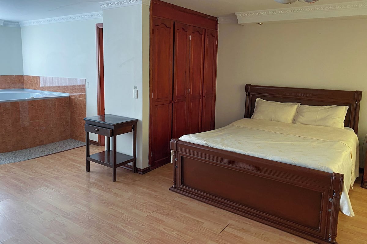 A bedroom with a wooden bed, a nightstand, and a wardrobe.