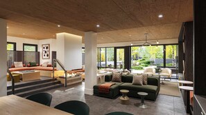 A modern living room with a fireplace, green sofas, and a view of the outdoors. - Charlie's Slopeside: Penthouse Ski-In/Out, Sleeps 10, Pool + Waterslide, Snowmass Base Village (Snowmass Village)