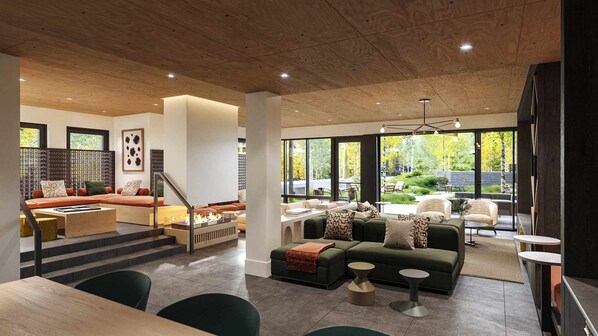 A modern living room with a fireplace, green sofas, and a view of the outdoors.