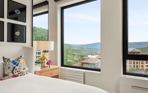 A bedroom with a large window, a bed, a nightstand, and a dresser. - Charlie Rentz: Penthouse Ski-In/Out, Sleeps 10, Pool + Waterslide, Snowmass Base Village (Snowmass Village)