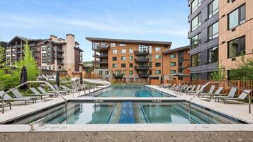 Une piscine avec des chaises longues et, en arrière-plan, un ensemble de bâtiments modernes.