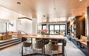 A modern interior with a dining area, seating, and a view through large windows.