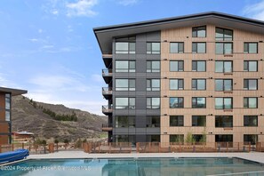 A modern multi-story building with a pool in front. - Charlie's Slopeside: Penthouse Ski-In/Out, Sleeps 10, Pool + Waterslide, Snowmass Base Village (Snowmass Village)