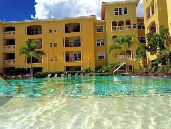 Guests can enjoy a refreshing swim in the hotel's pool surrounded by palm trees and lounge chairs.
