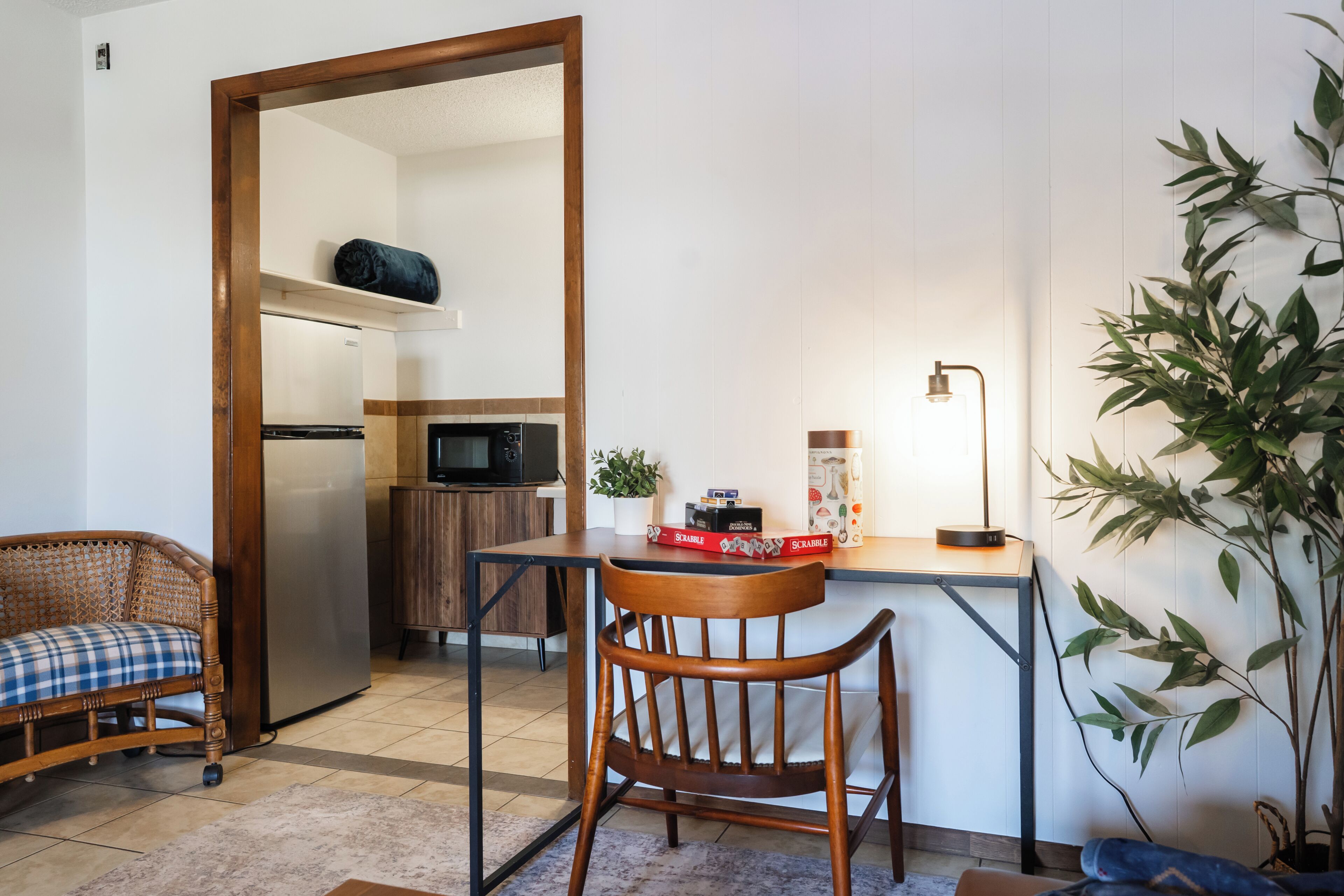 A compact living space with a kitchenette, a dining area, a sofa, and a potted plant.