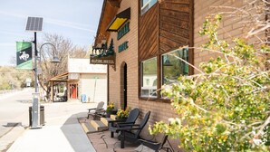 A building with a sign reading 'Alpine Motel,' outdoor seating with chairs, and a solar panel on the roof.