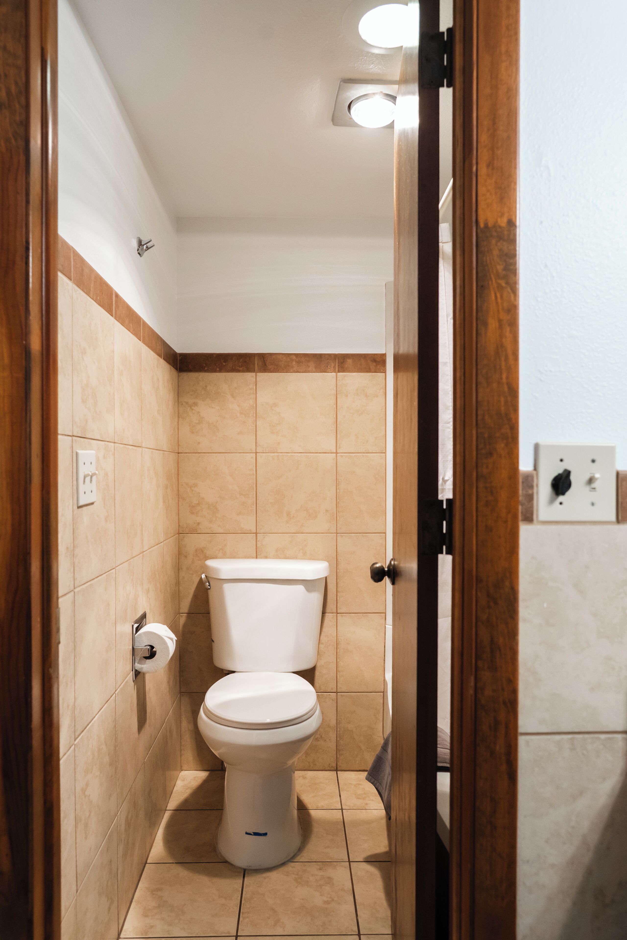 Een badkamer met een toilet, een handdoekhouder en een wandlamp.