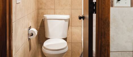 Een badkamer met een toilet, een handdoekhouder en een wandlamp.