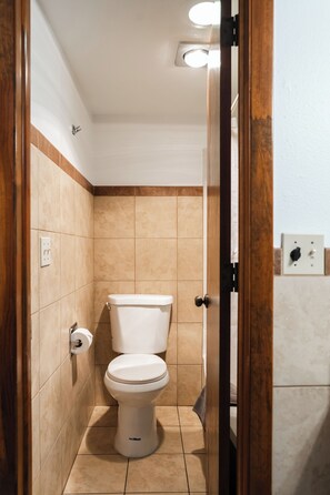 A bathroom with a toilet, a towel rack, and a wall-mounted light fixture.
