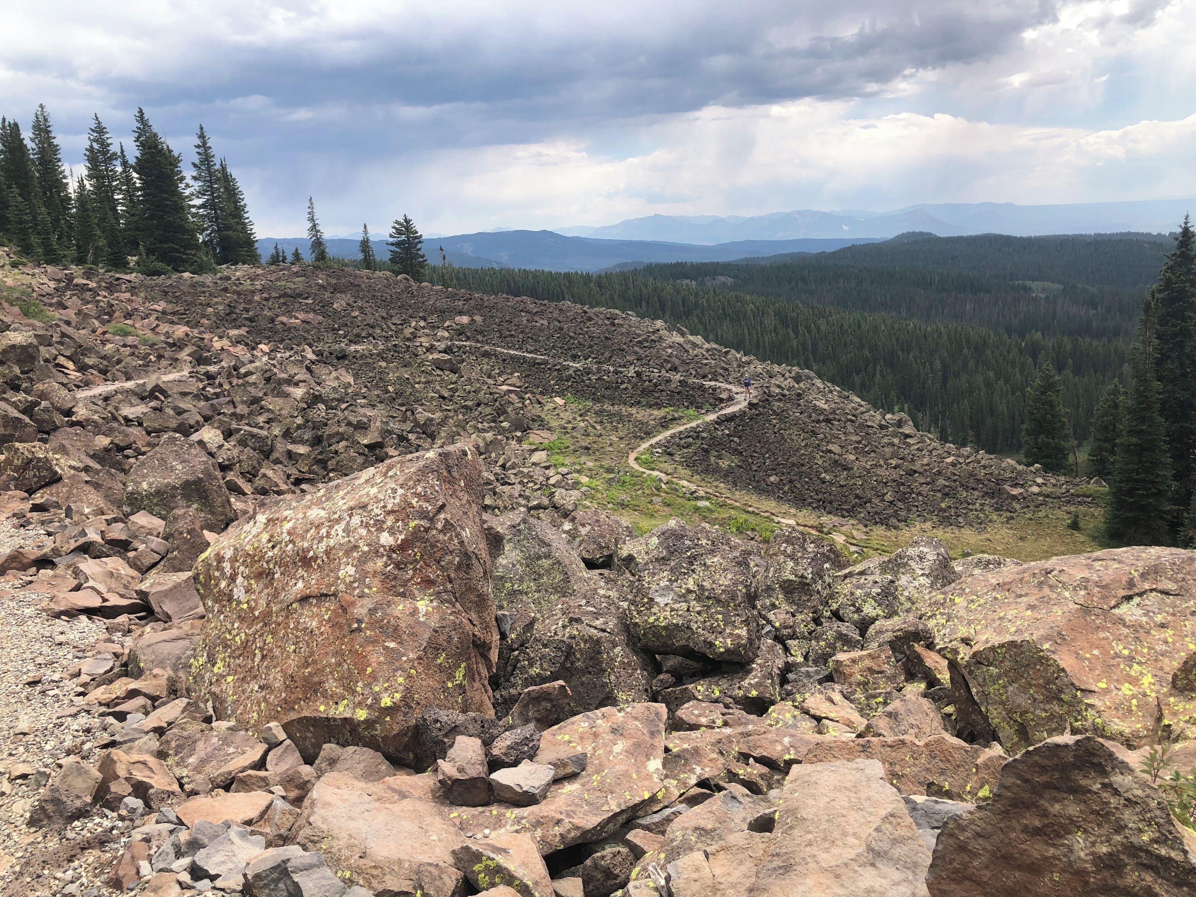 A rocky mountain landscape with a winding path and dense forest.