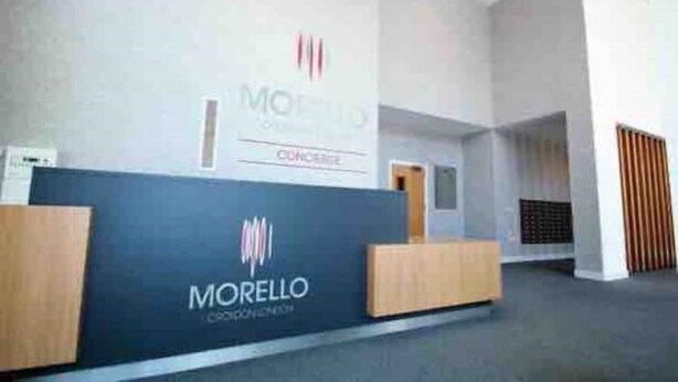Una zona de recepción con un mostrador azul, un logotipo y una puerta al fondo.
