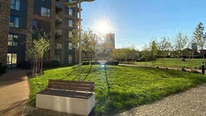 Un edificio moderno con un sendero pavimentado y una zona verde con árboles jóvenes.
